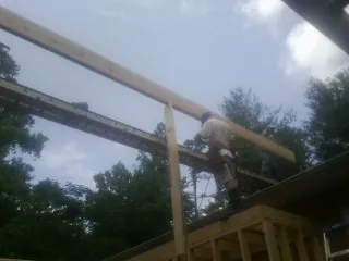 Carpenter setting a ridge beam over a new addition frame — Ice Dam Removal by Roofing Brothers in Manito