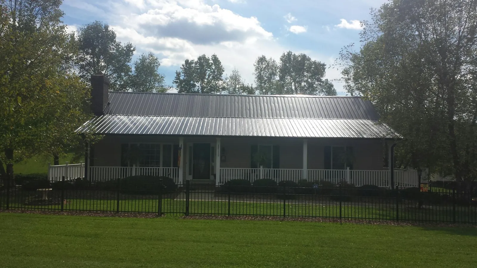 Gray metal roof on a brick ranch with a full width front porch — Gutter Guard Installation work by our crew in Manito