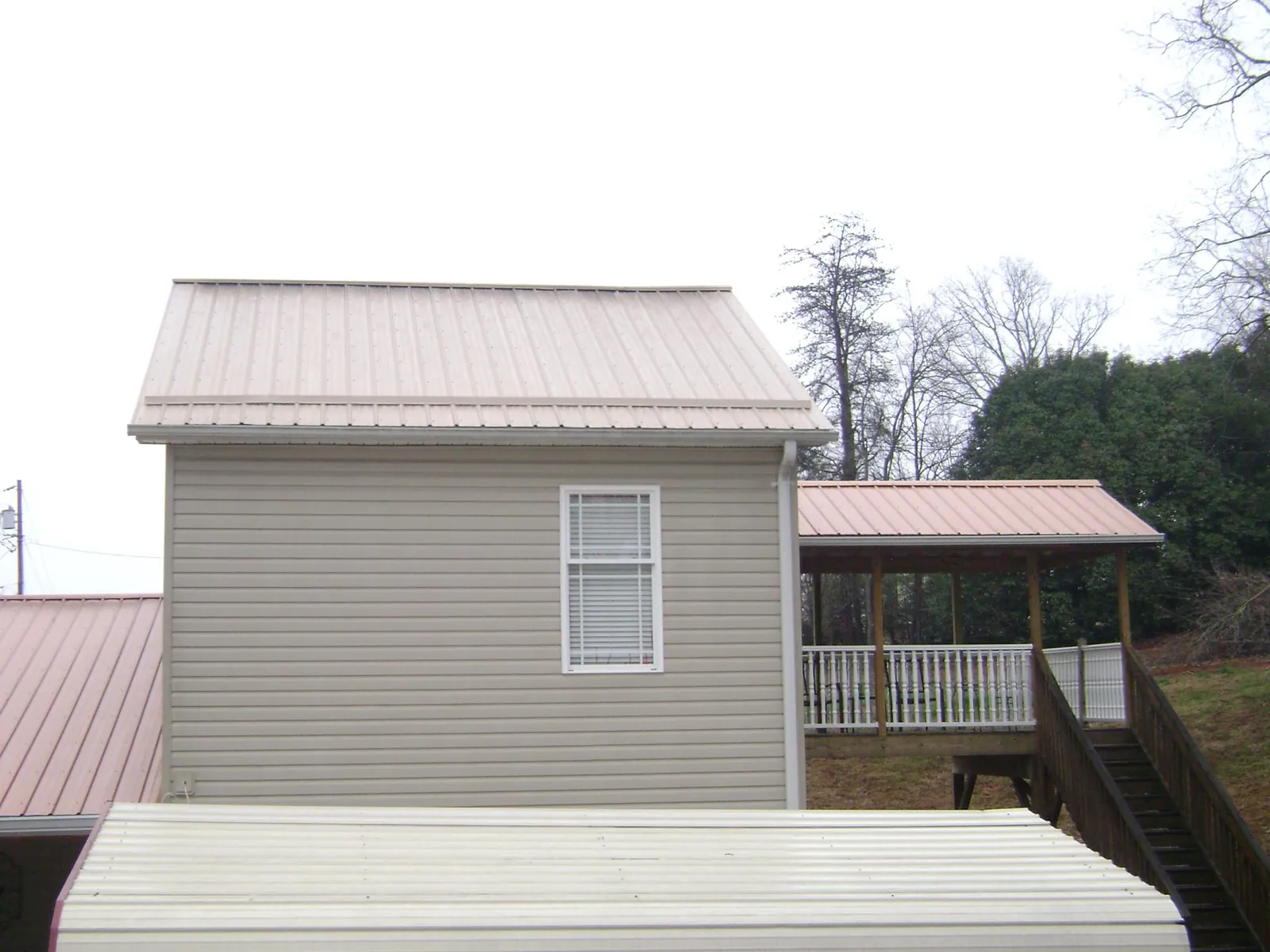 Tan metal roofs on a two story addition and attached porch, from a Roof Replacement job in Manito